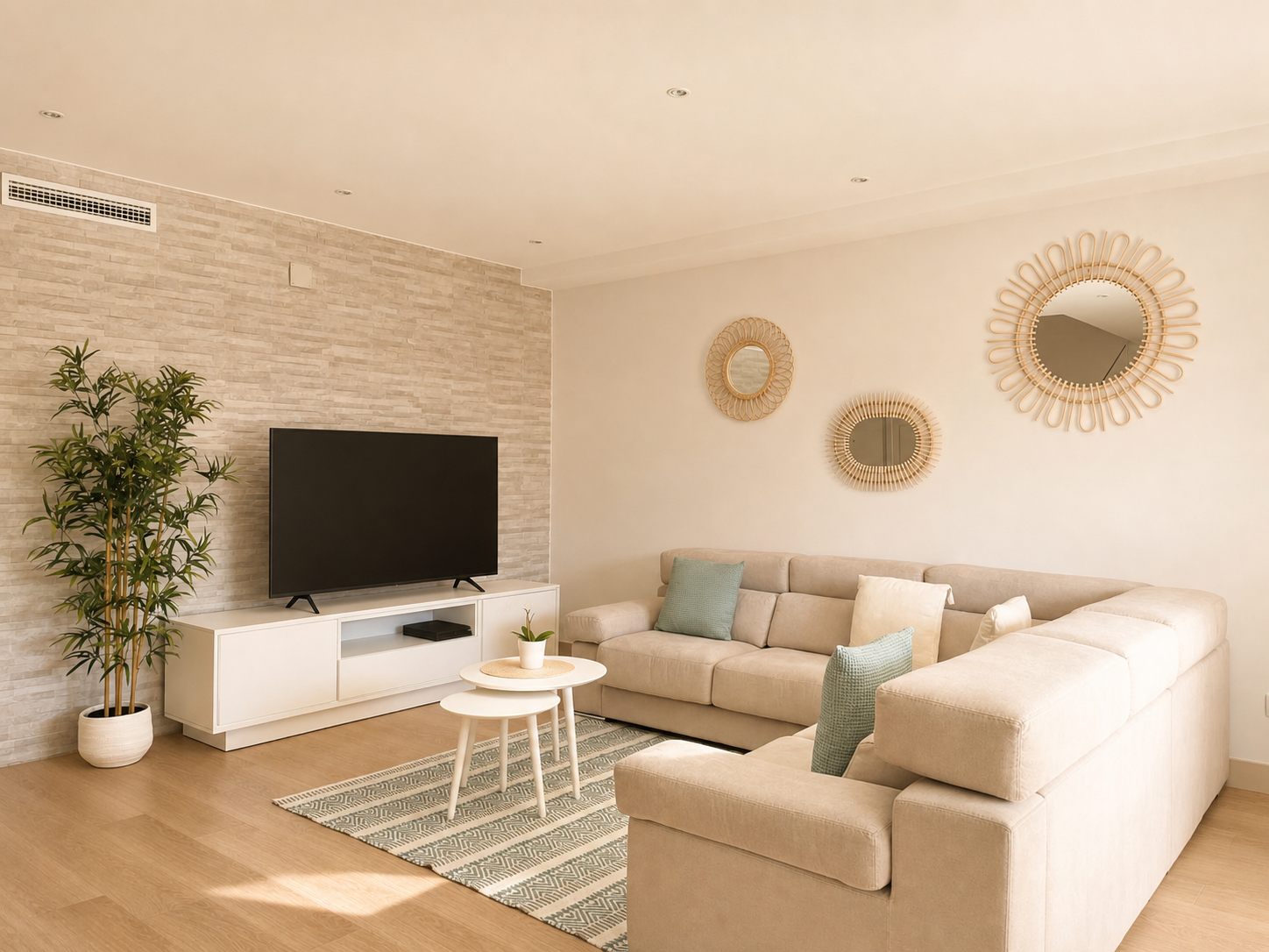 Salón con sofá en tono arena, mesa auxiliar de madera y espejos decorativos