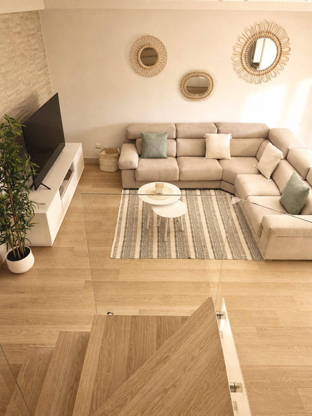 Vista cenital del salón con escalera de madera y cristal
