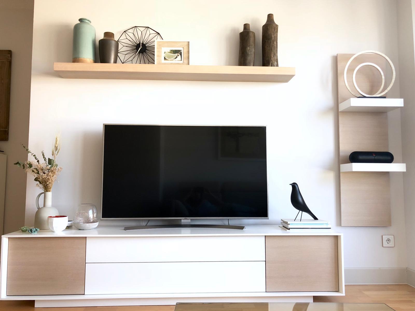 Detalle de estilismo: balda de madera con objetos decorativos y mueble bajo en tonos neutros