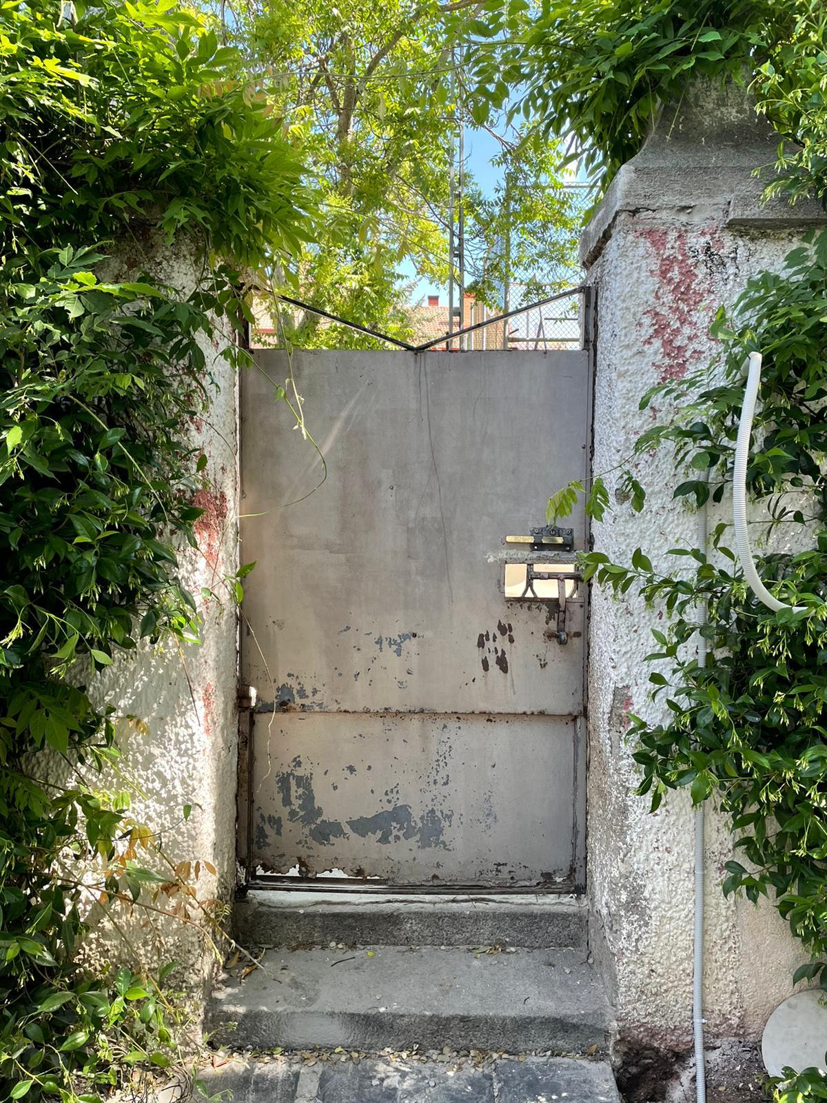 Puerta de hierro oxidada en un muro de jardín, antes de la reforma