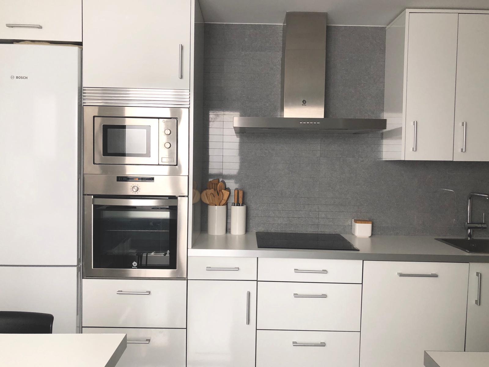Cocina reformada en blanco con campana de acero inoxidable
