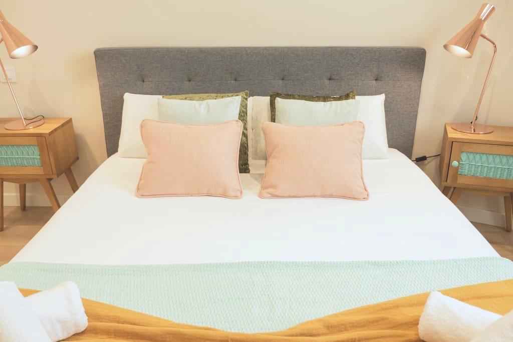 Dormitorio con cabecero gris y cojines en tonos neutros